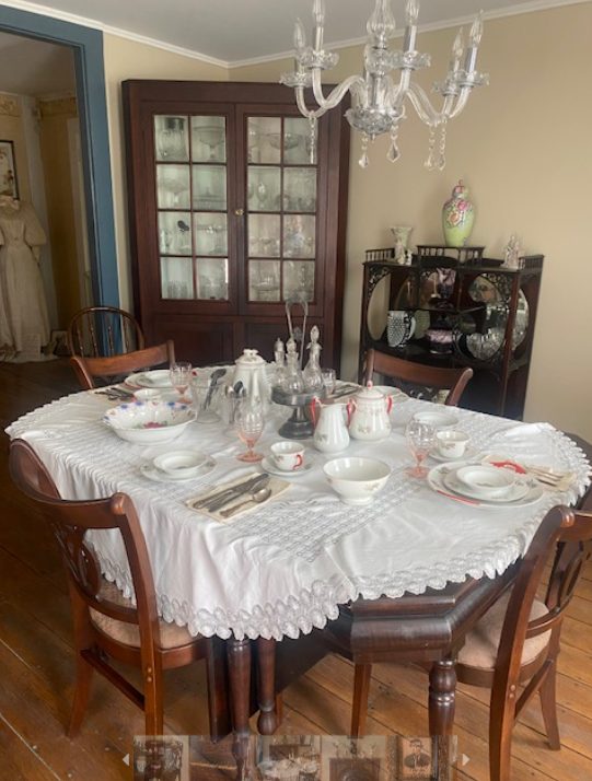 The tavern dining room set with china and lace under a crystal chandelier