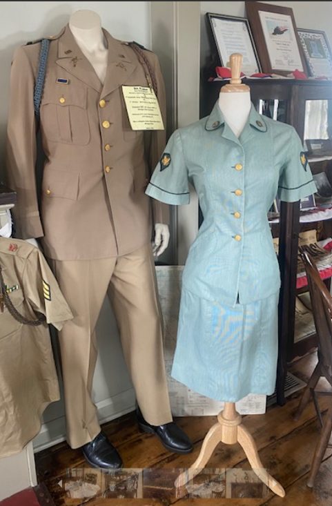 A tan Army dress uniform beside a light-blue women's service uniform